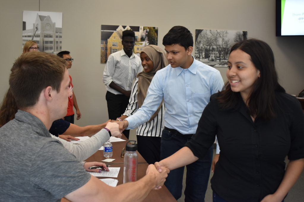 adults and students shaking hands